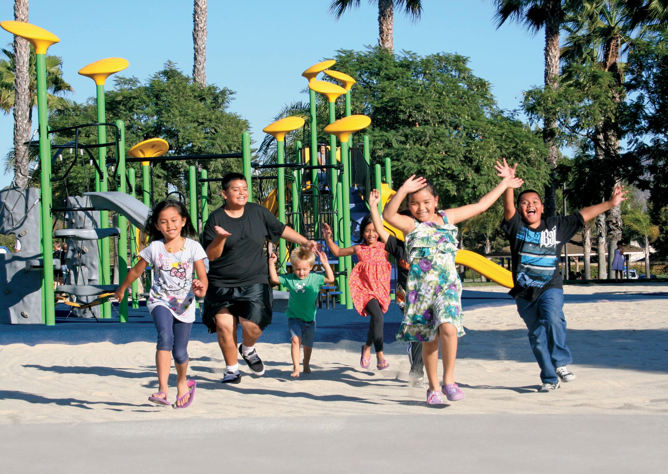 6 children runnning on the sand in a playground